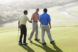 Men on golf course putting green shaking hands